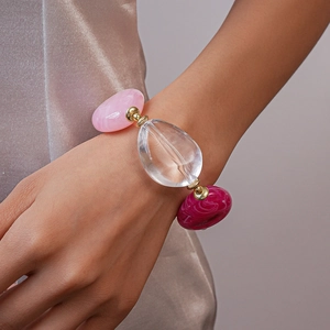 Close-up of irregular pink and rose acrylic beads on a stylish bracelet with gold accents