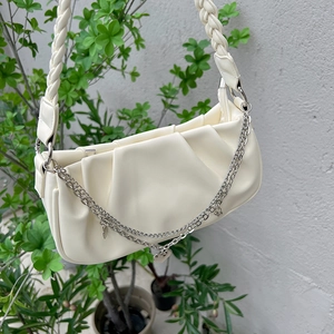 Detail of white pleated cloud bag with silver chain and heart-shaped pendant accent