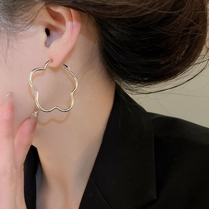 Detailed view of silver-tone hollow flower hoop earrings worn for a vintage retro aesthetic