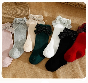 Detail view of colorful knit knee-high socks featuring large decorative satin bows