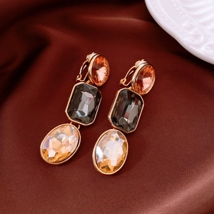Detailed shot of vintage gold earrings with pink and grey crystals on red silk