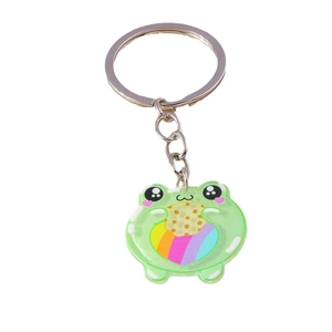 Cute green frog keychain holding a cookie with a rainbow pattern on white background