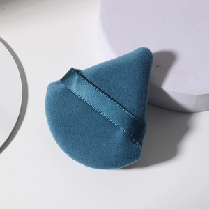 Borla de maquillaje azul de terciopelo con cinta de raso en fondo blanco minimalista