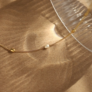 Minimalist freshwater pearl necklace in 18k gold-plated titanium steel with water-like shadows