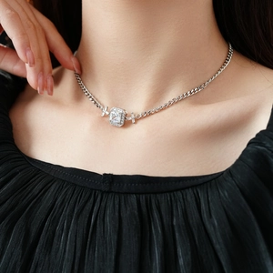 Gros plan d'un collier argenté avec pendentif zircon rectangle et croix sur un mannequin