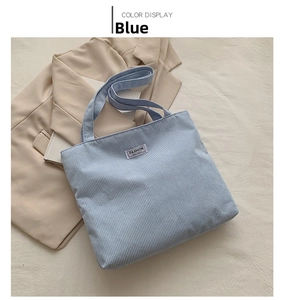 Close-up of light blue corduroy tote bag featuring a stitched Fashion Instinct label