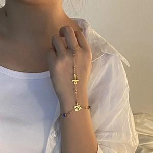 Detail of gold hand chain with Ankh cross, Eye of Horus charms and blue beads
