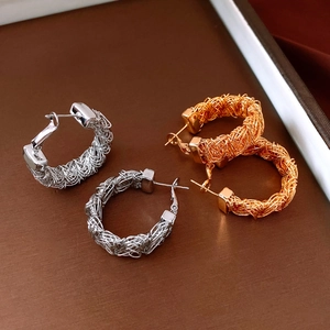 Close-up of gold and silver hoop earrings featuring an intricate woven wire texture