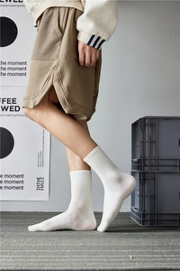 Detail of white ribbed cotton mid-calf socks shown on a model in a lifestyle setting