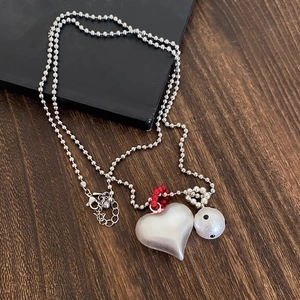 Silver bead necklace with heart pendant and colorful accent beads on dark wood
