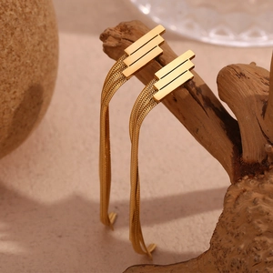Close-up of gold geometric fringe chain earrings hanging on an artistic wood branch