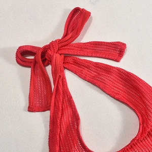 Detailed close-up of red mesh fabric with a tied bow knot and ribbed knit texture
