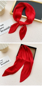 Close-up of vibrant red pleated silk scarf with fine accordion folds on minimalist background