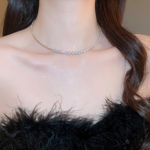 Close-up of V-shaped silver necklace with geometric rhinestones worn by a model