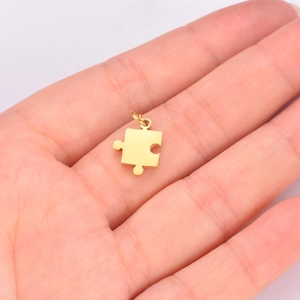 Macro shot of small gold puzzle pendant with ring holder held in a person's palm