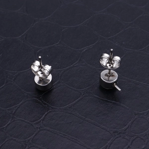 Minimalist stainless steel stud earrings with butterfly backs on dark background
