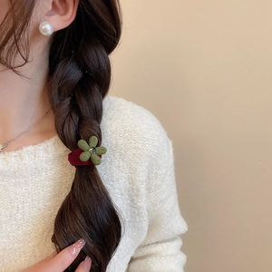 Détail d'un chouchou fleur rouge sur un chignon tressé avec boucles d'oreilles perles