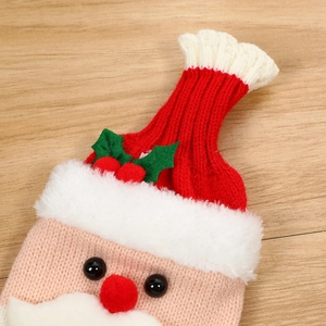 Knitted Santa Claus wine bottle cover in red and white on a light wooden background