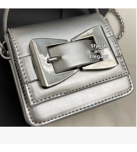 Close-up of metallic silver mini crossbody bag featuring a large metal bow buckle and chain