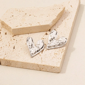 Macro view of silver heart stud earrings with unique lava texture on stone surface