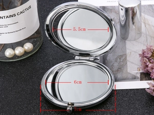 Detail of folding compact mirror with 7cm silver metal frame showing internal dual mirrors