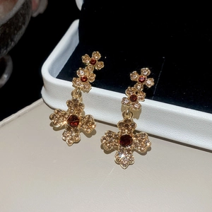 Detail of vintage gold flower earrings with red-brown gemstones and sparkling crystals