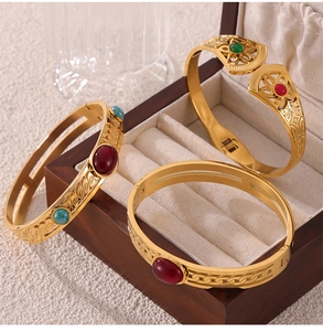 Macro shot of three gold-plated titanium bangles with hollow carvings and natural stones