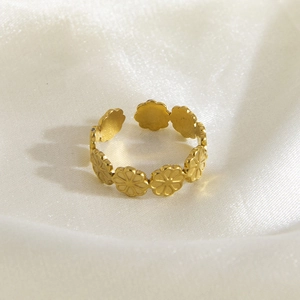Detailed close-up of golden adjustable daisy flower ring on white silk fabric background