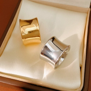 Detailed close-up of wide polished metal rings in gold and silver on satin lining