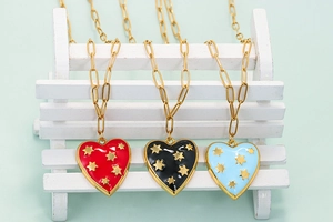 Detailed view of heart pendant necklaces with gold stars on a white wooden display stand