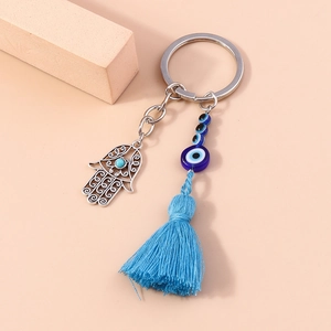 Hamsa Hand Evil Eye Keychain with blue beads and tassel on minimalist beige background
