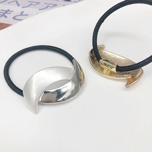 Detailed view of curved gold and silver metal moon-shaped ponytail holders on black elastic