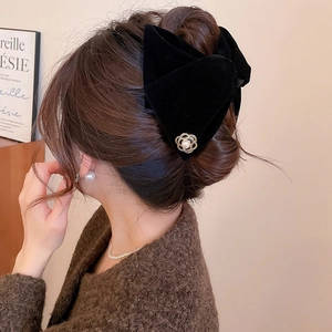 Détail de la pince à cheveux en velours noir avec pétales dorés et perle sur cheveux