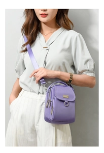 Detail view of purple nylon crossbody bag with multi-layer zippers and wide strap