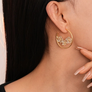 Gros plan de créoles dorées ornées de fleurs en zircon portées par un mannequin