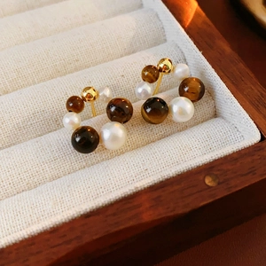Close-up of gold-plated hoop earrings with white pearls and brown tiger eye beads