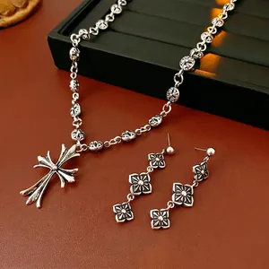 Vintage oxidized silver cross necklace and flower earring set on luxury display