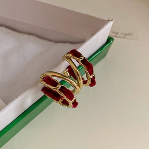 Detail of vintage gold metal earrings with deep red velvet fabric in spiral geometry shape