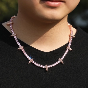 Close-up of a rose gold thorn necklace with pink zircons worn by a model on a black tee