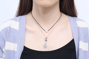 Detail of layered necklace with white pearl and heart pendant engraved with Love