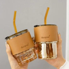 Détail de gobelets en verre ambré avec manchons en cuir marron et pailles assorties