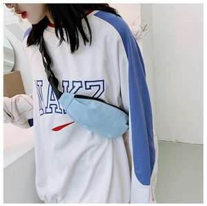 Detail of light blue canvas waist bag with adjustable strap shown on model for size scaling