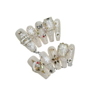 White Christmas press-on nails featuring snowflakes and 3D tree charms in long coffin shape