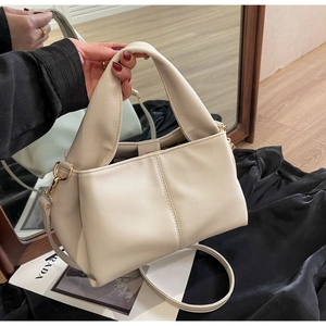 Close-up of beige lychee texture shoulder bag with wide handle and gold hardware