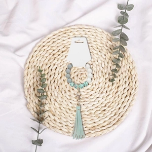 Grey and turquoise silicone bead keychain with tassel on a display card and woven mat