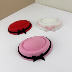 Three elegant wool felt pillbox hats in red, white, and pink with contrast bow ribbons