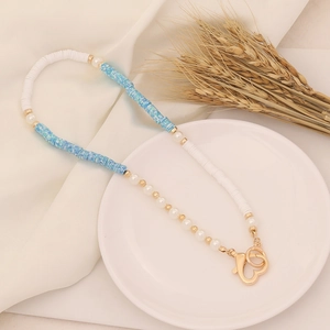 Detail of bohemian polymer clay necklace with white and blue beads, pearls and heart clasp