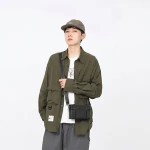 Dettaglio di una borsa a tracolla alla moda abbinata a una giacca utility verde e cappello