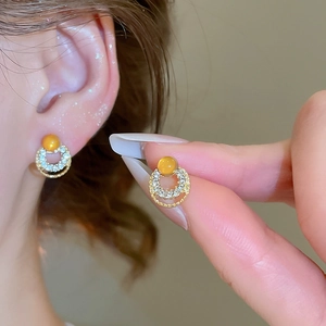 Detailed macro view of gold geometric hoop earrings with opal and sparkling zircons
