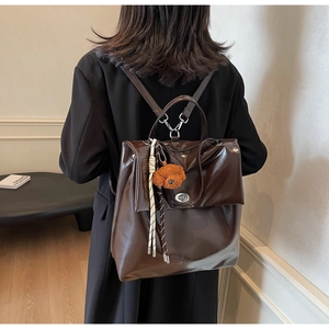 Detail of dark brown leather backpack featuring a silver twist lock and plush puppy charm